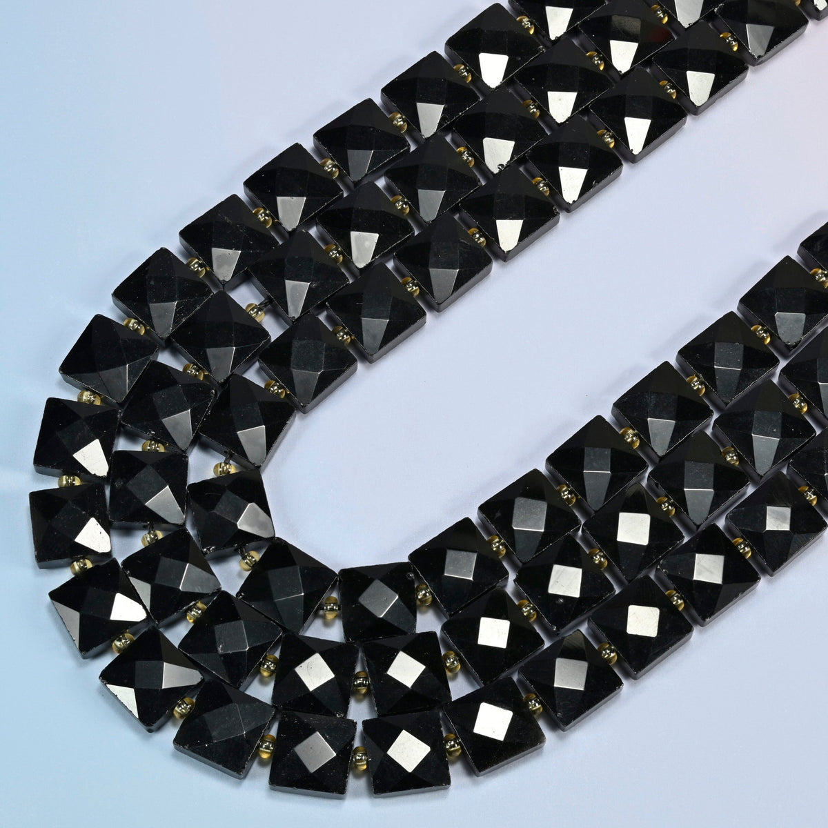 Natural black onyx faceted flat square beads in several strands curved into a wide U, solid glossy black stone