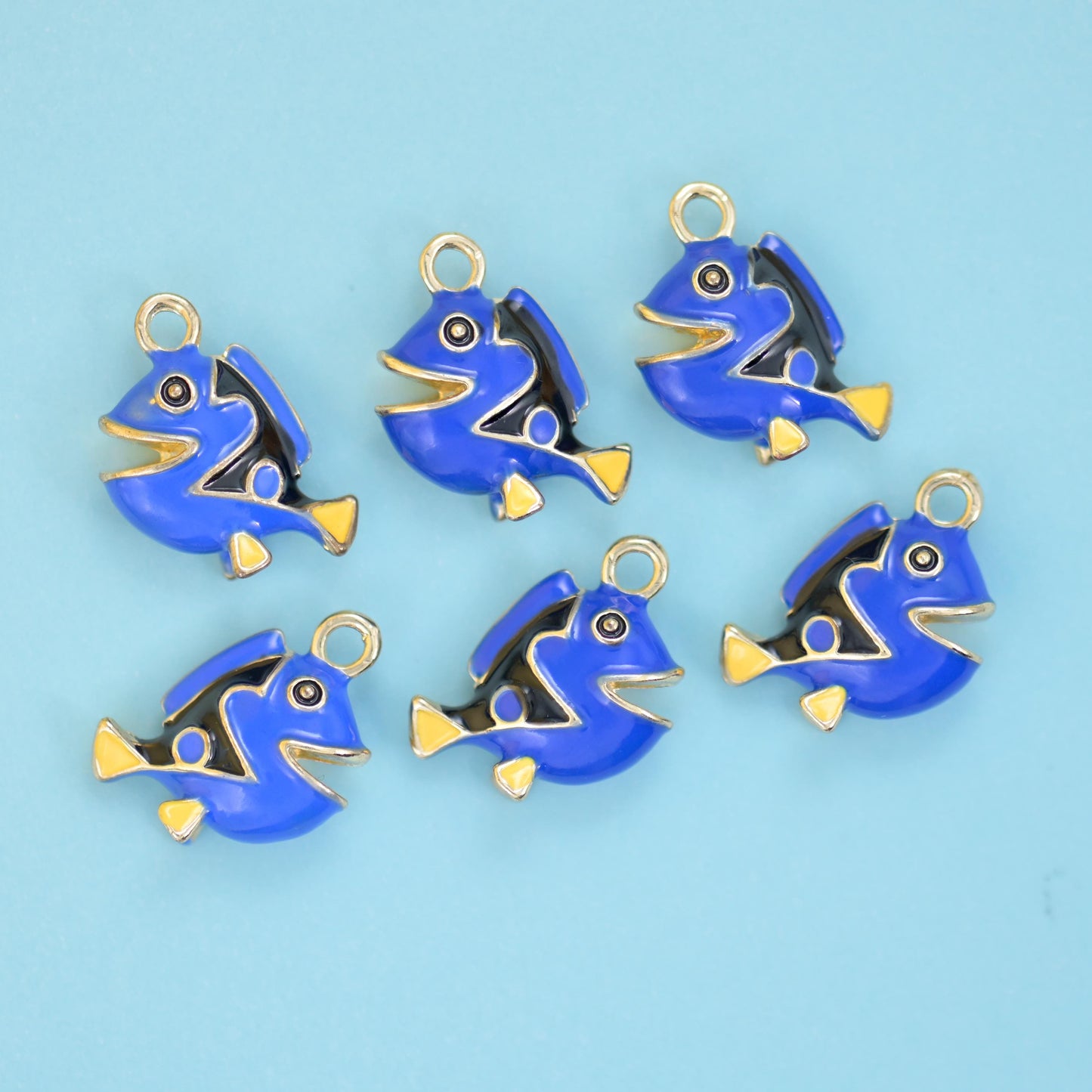 A round-bodied reef fish in bright royal blue enamel with a black sweep across the back, a white belly and pale gold fins…