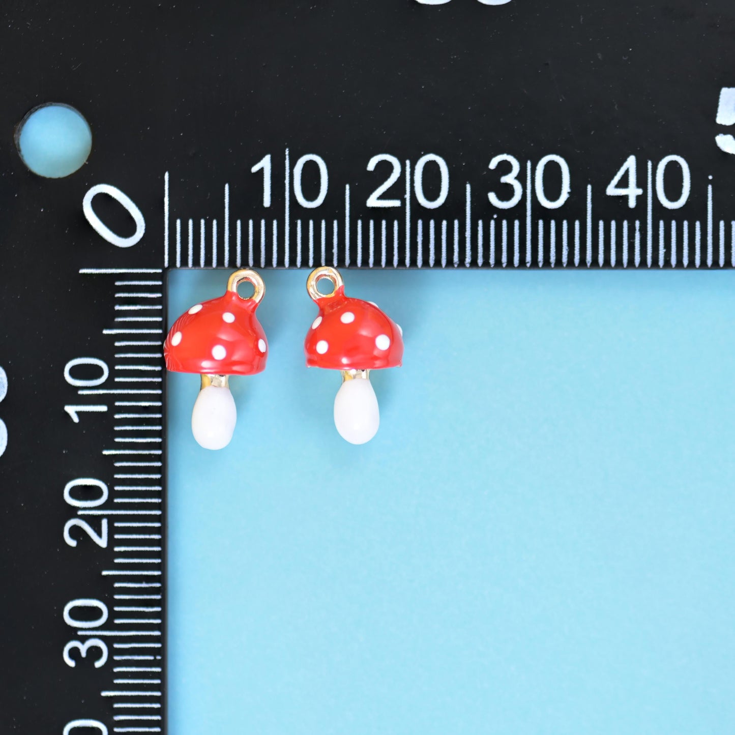 A tiny toadstool with a glossy tomato red cap dotted in white and a smooth ivory white stem
