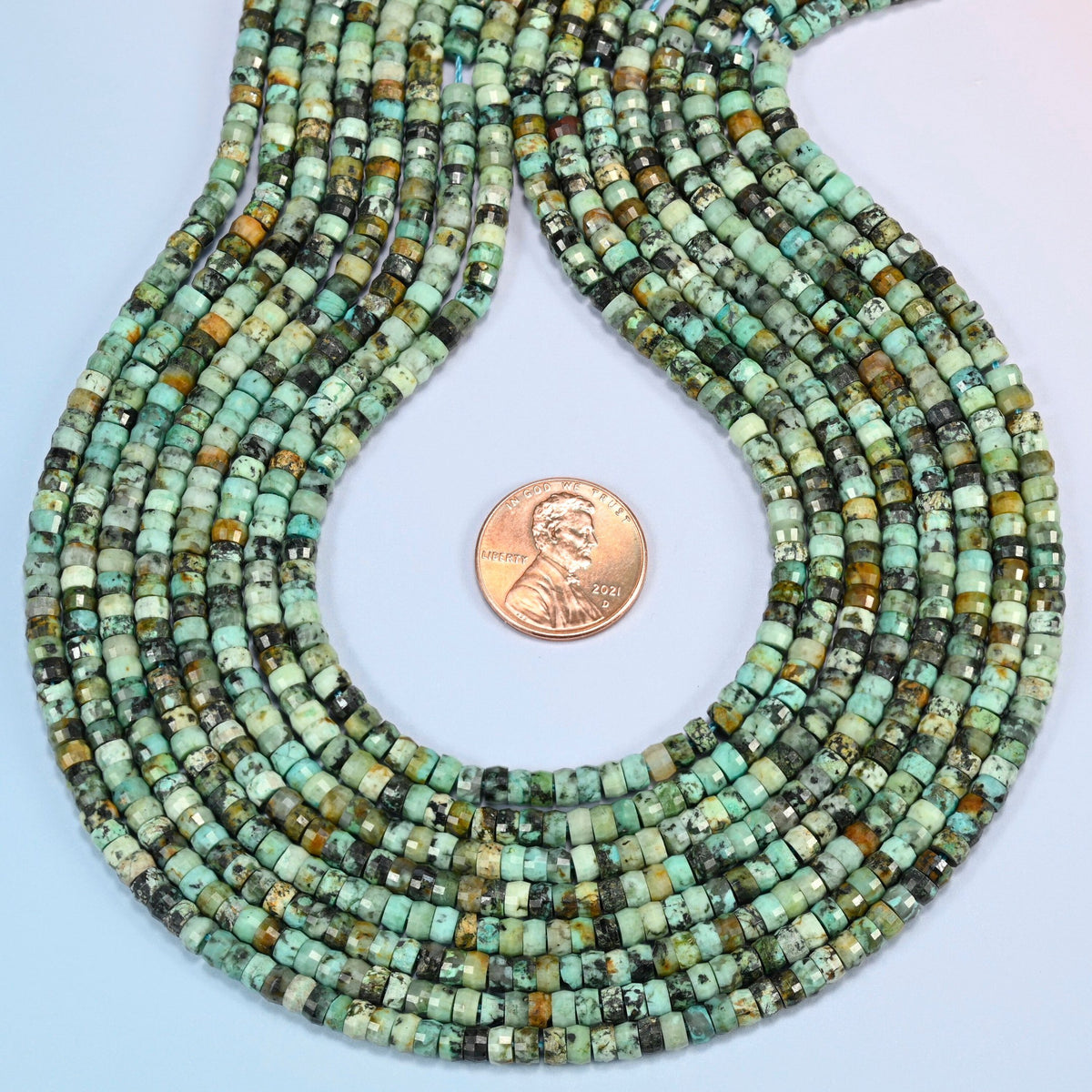 African howlite faceted heishi disc strands formed into a teardrop loop around a US penny for scale