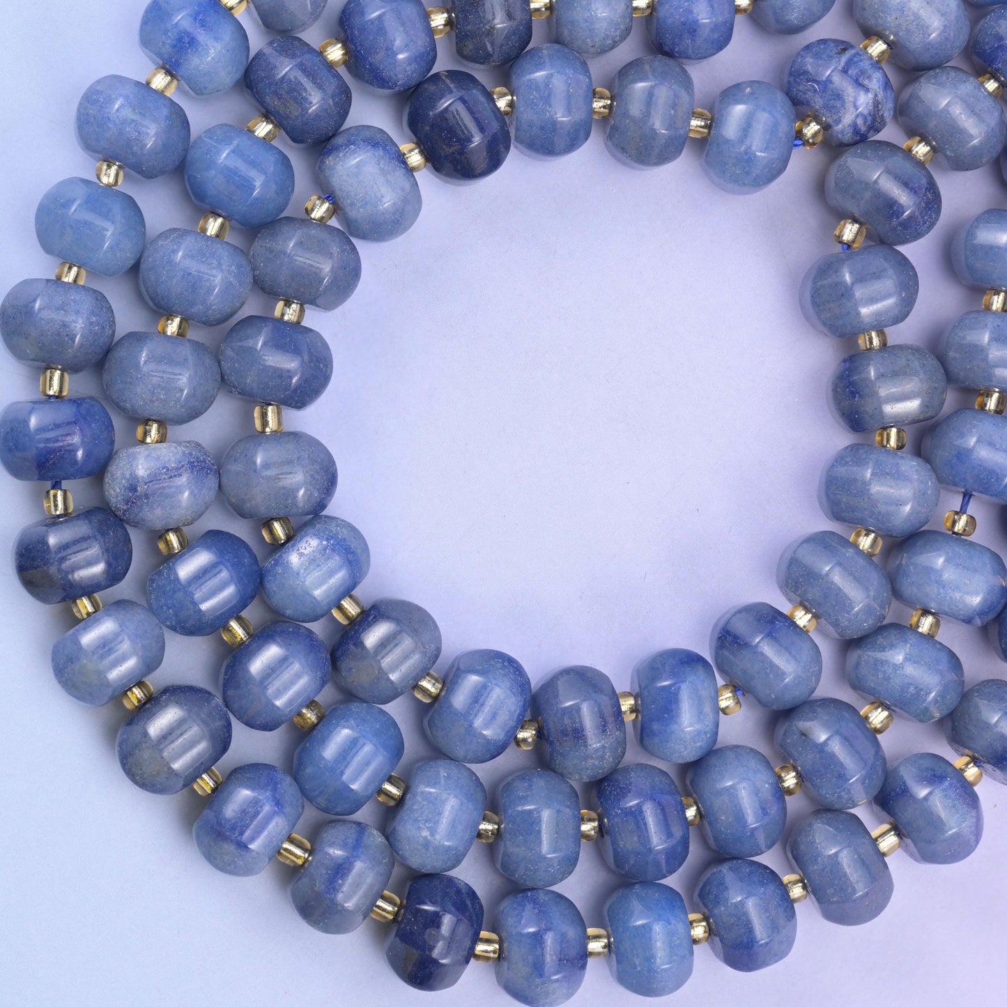 Wide open loop laid flat, brass discs marking an even rhythm between every ribbed bead