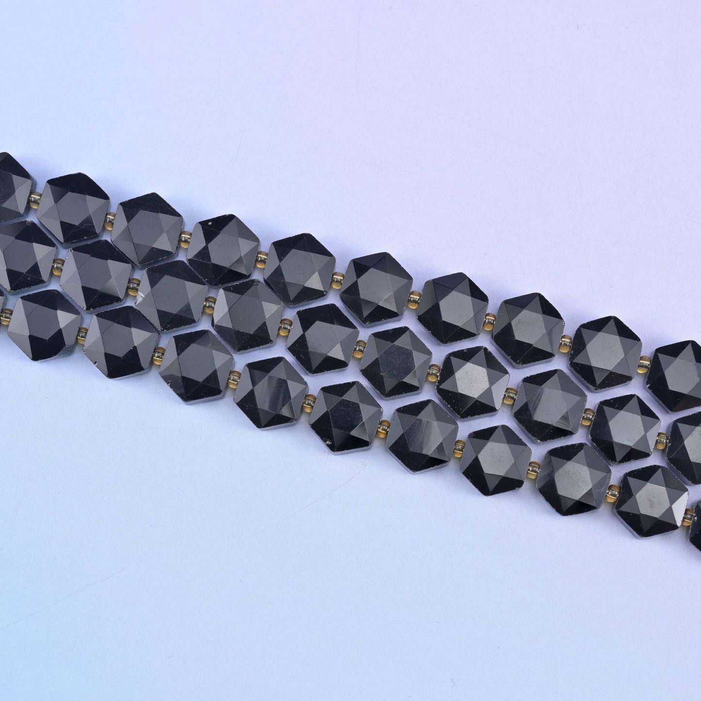 Two strands of 12mm obsidian hexagons stretched diagonally, flat discs lying in an even row