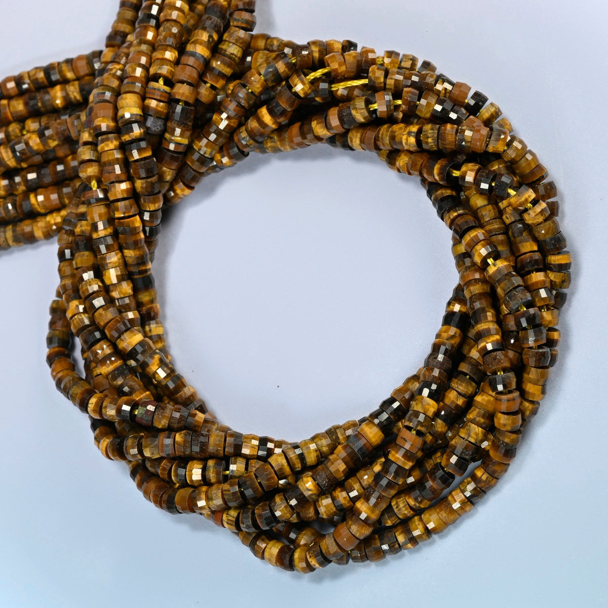 Tiger eye faceted heishi disc beads coiled into overlapping loops, whole strands of warm golden brown stone