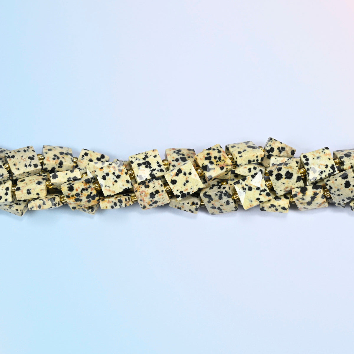 Strands of dalmatian jasper faceted flat square beads twisted together in a horizontal row