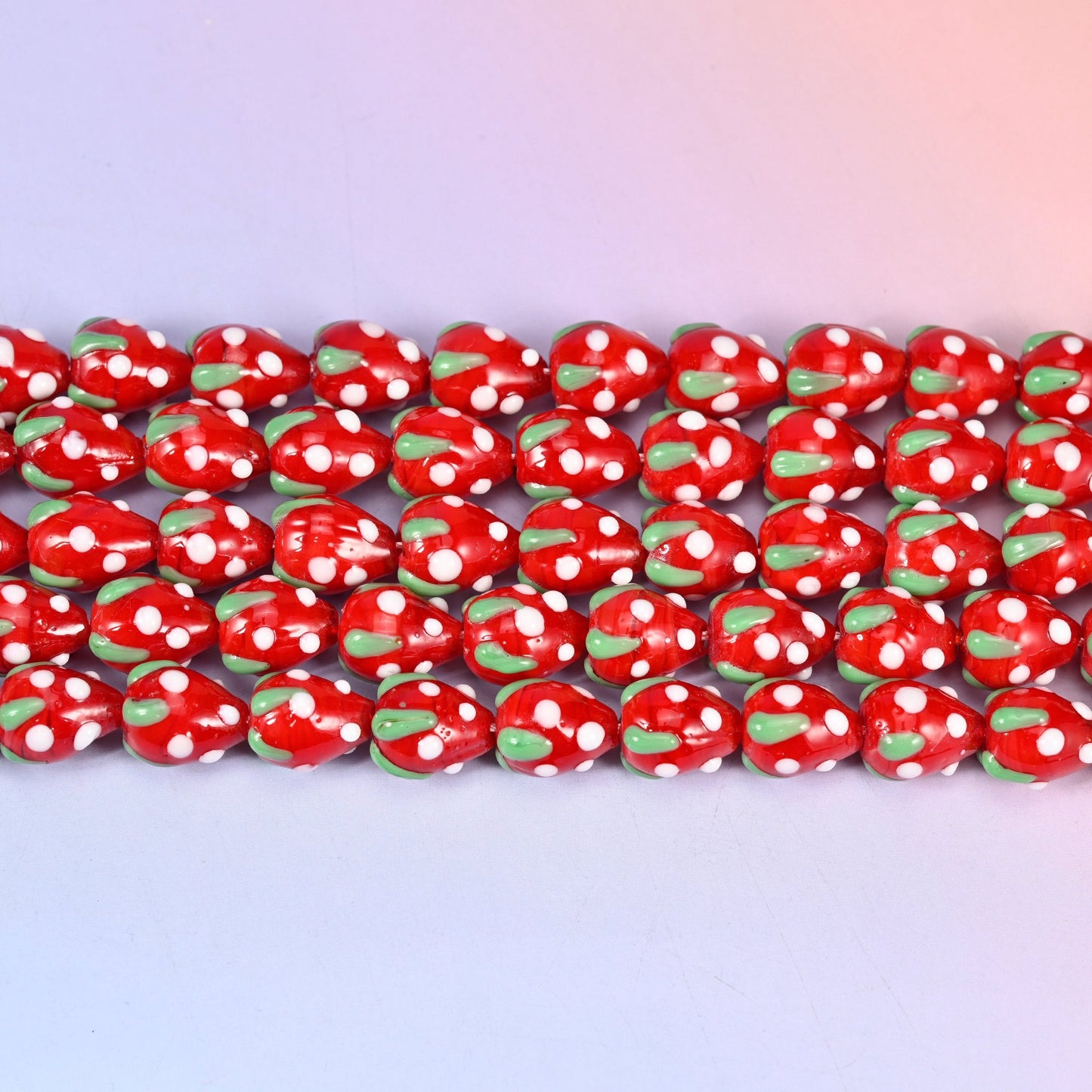 Glossy postbox red strawberry glass beads dotted with white seeds and a green leaf cap