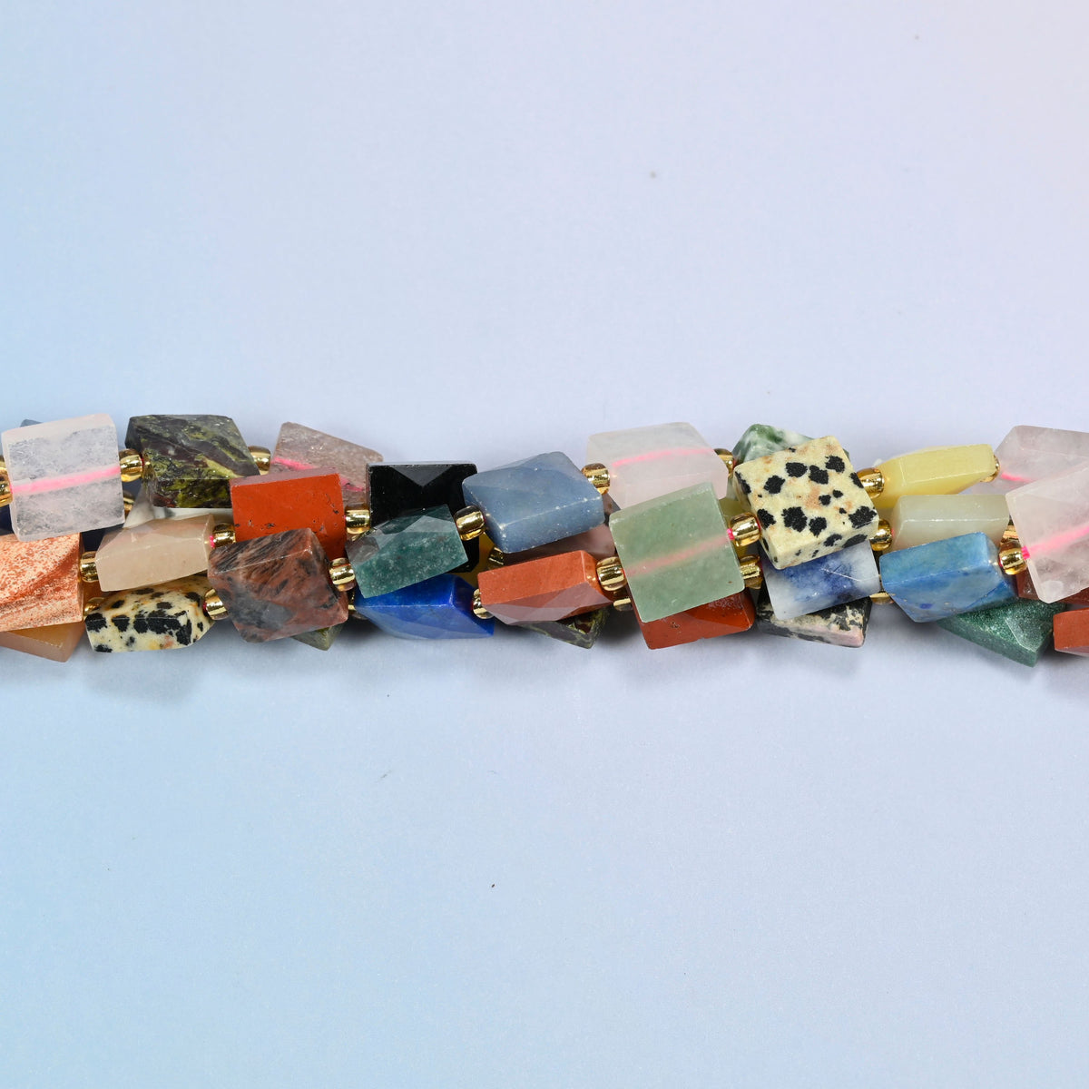 Strands of assorted gemstone faceted flat square beads twisted together in a horizontal row