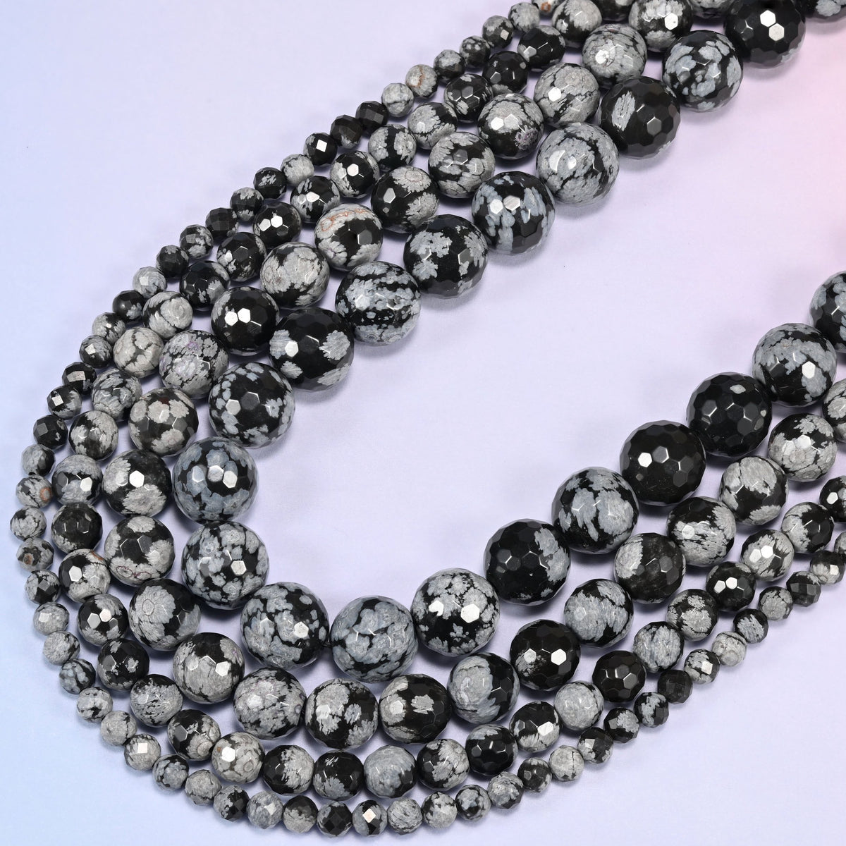Snowflake Jasper faceted round beads coiled into an open teardrop-shaped loop, graduating from small to large along the strand.