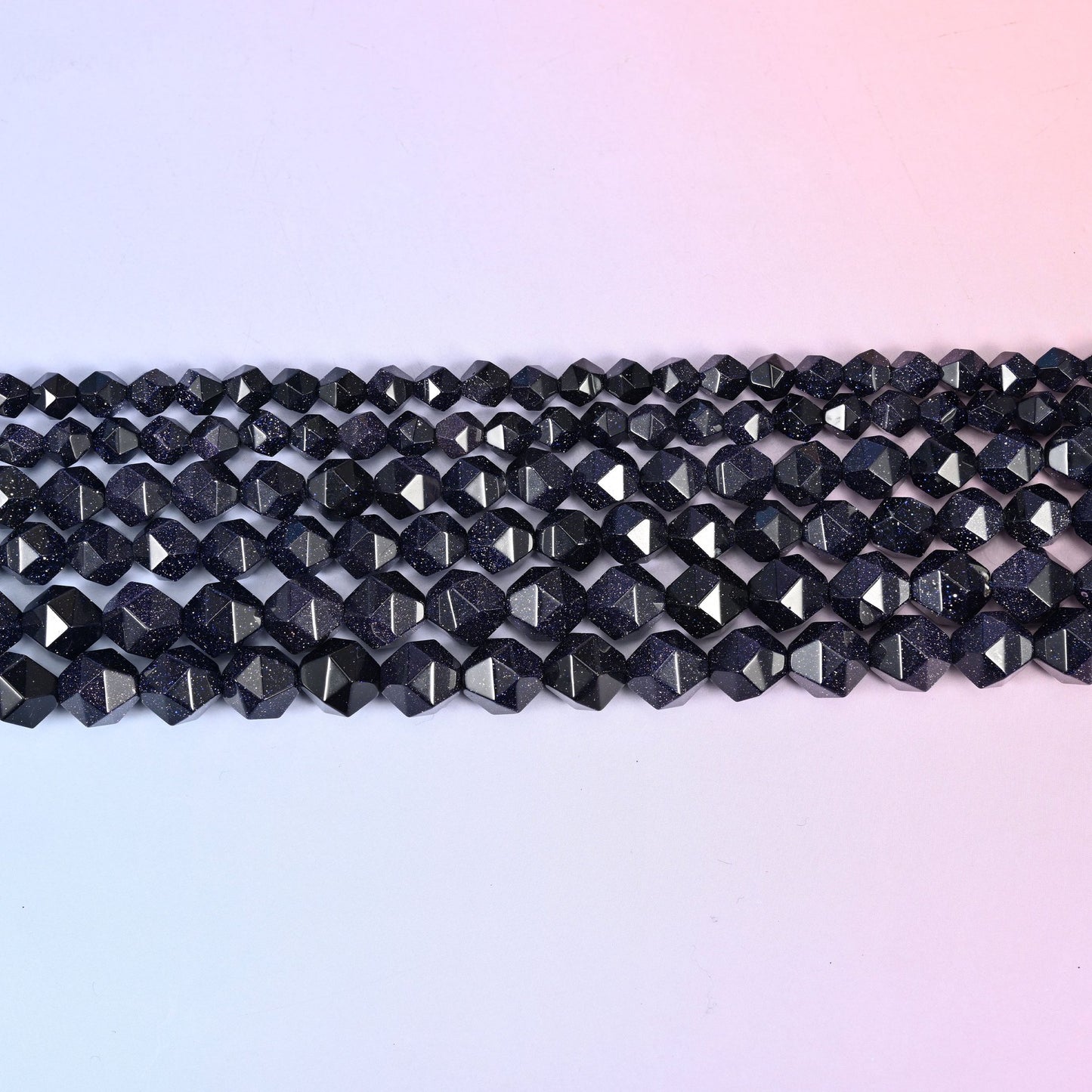 Straight rows of star cut blue sandstone beads laid flat, showing the even faceted points