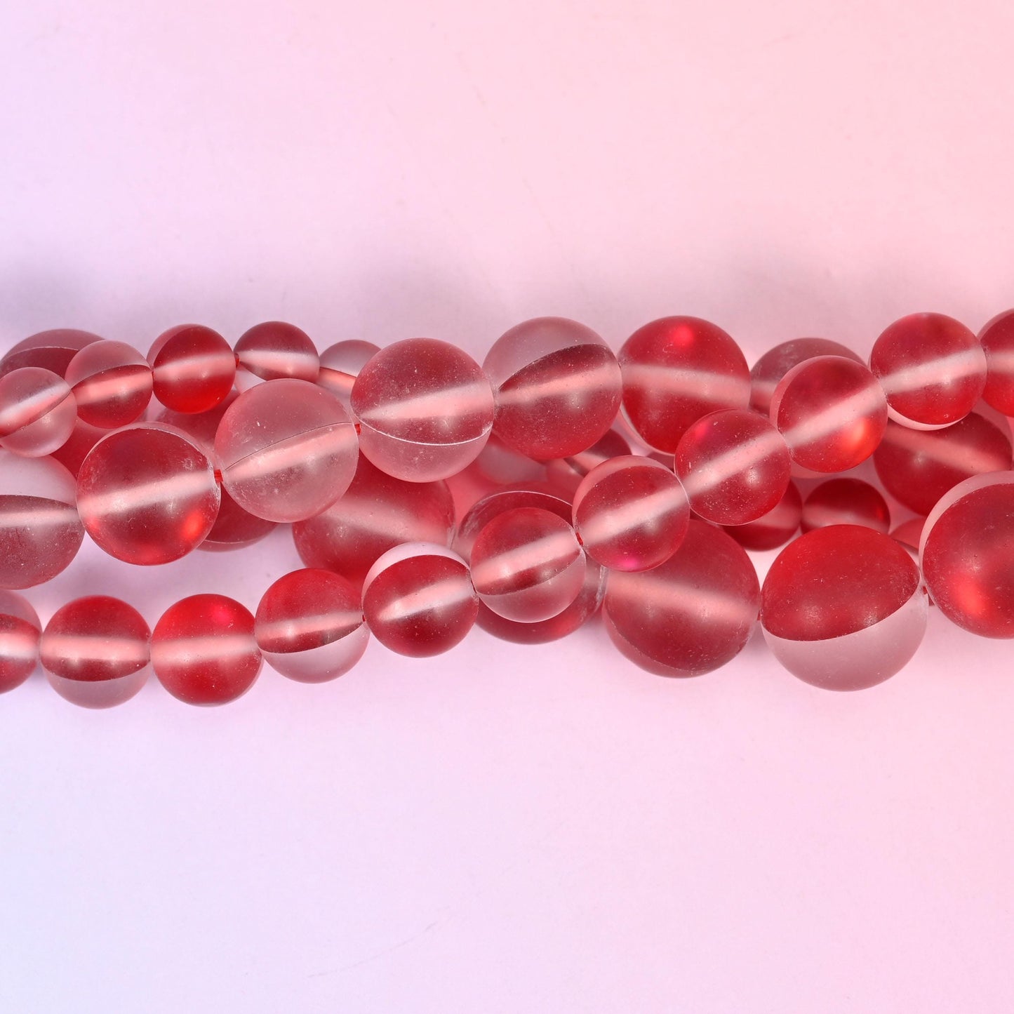 Frosted cherry-red glass beads with a soft sanded surface and iridescent core