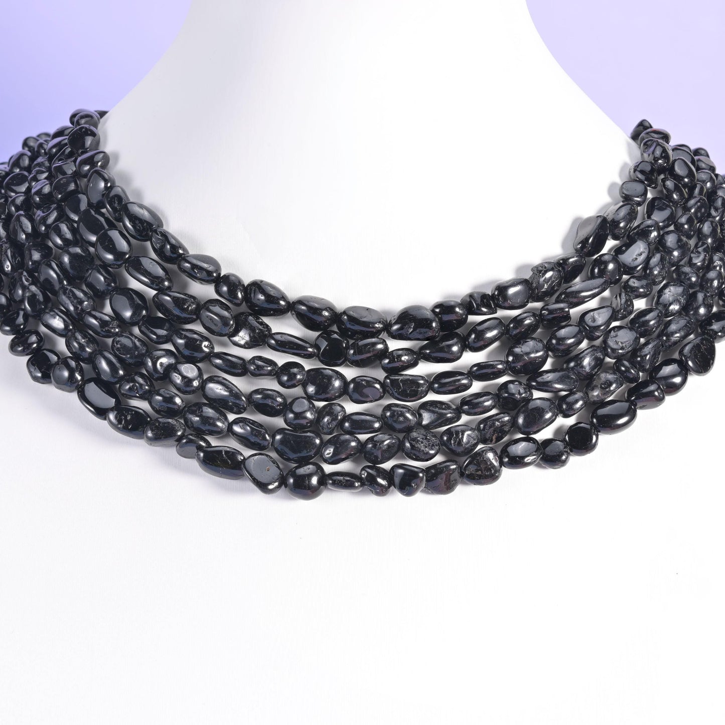 Black tourmaline pebble beads worn on a white bust as a multi-strand collar