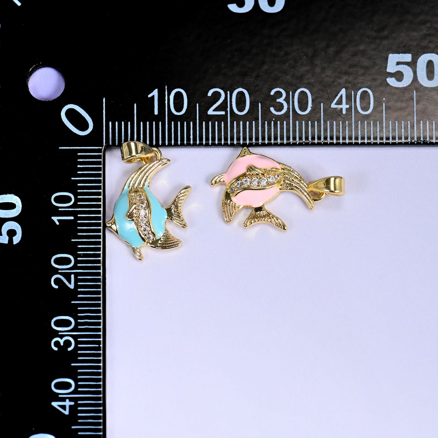 Turquoise and pink Enamel Tropical Fish Zirconia Charms on a black millimeter ruler, both colorways shown against the mm scale.