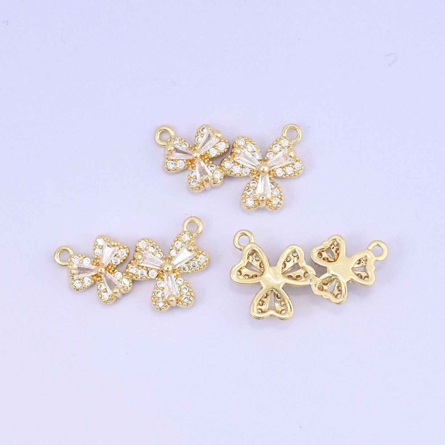 Three small flower blossoms set side by side, each petal pave set with clear zircon and outlined in warm gold