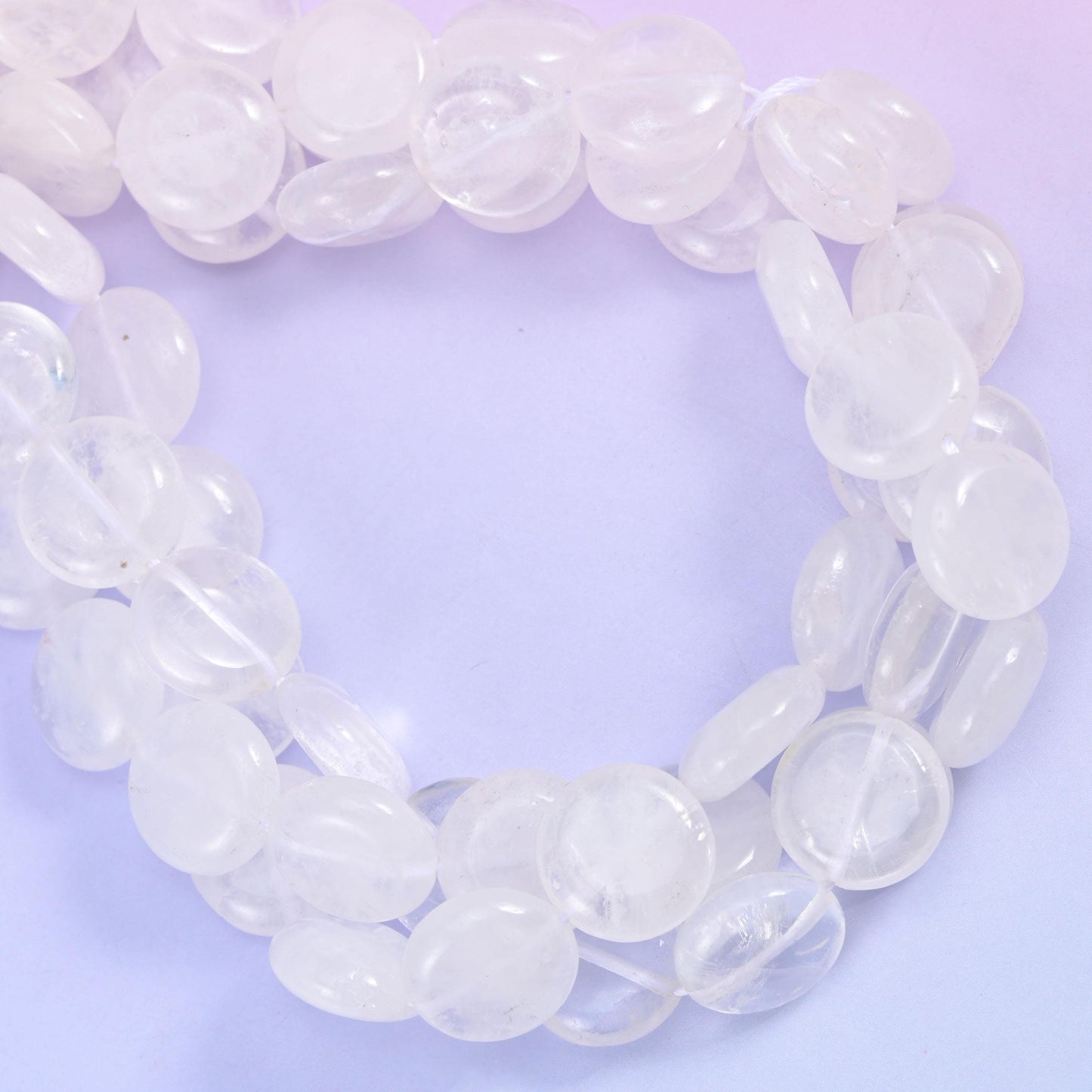 Open ring of clear quartz coins photographed from above, showing bead thickness and drill placement