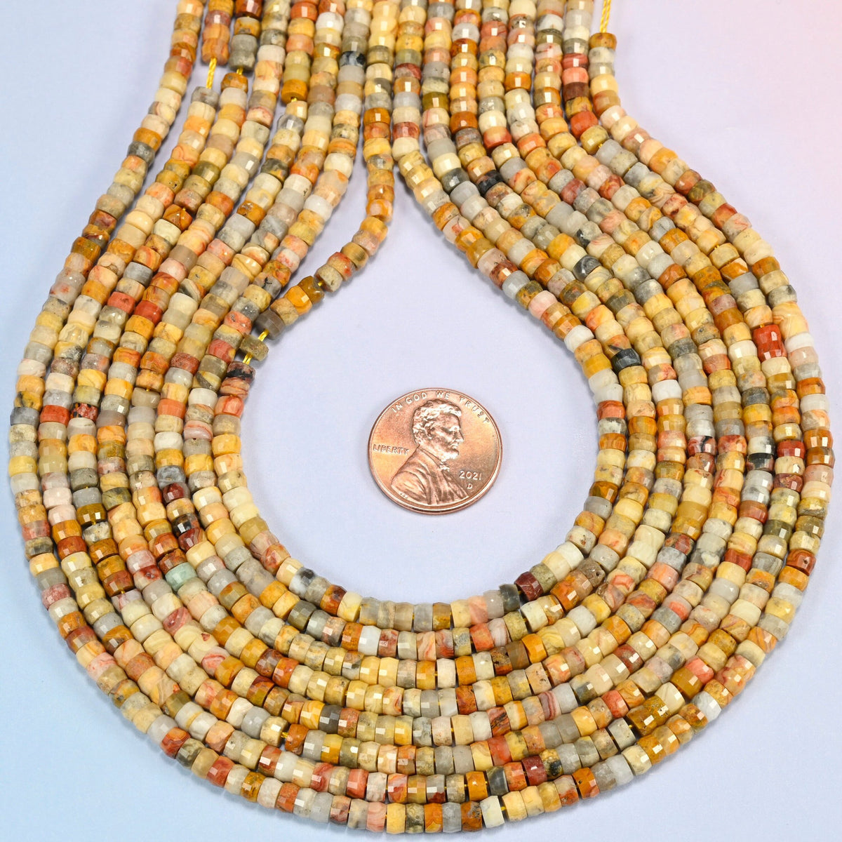 Crazy agate faceted heishi disc strands formed into a teardrop loop around a US penny for scale