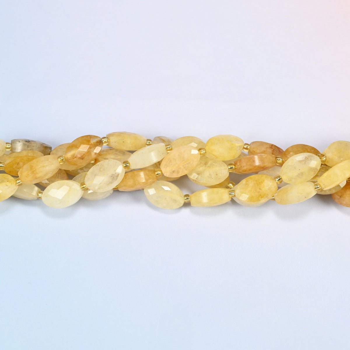 Strands of golden healer quartz faceted flat oval beads twisted together in a horizontal row