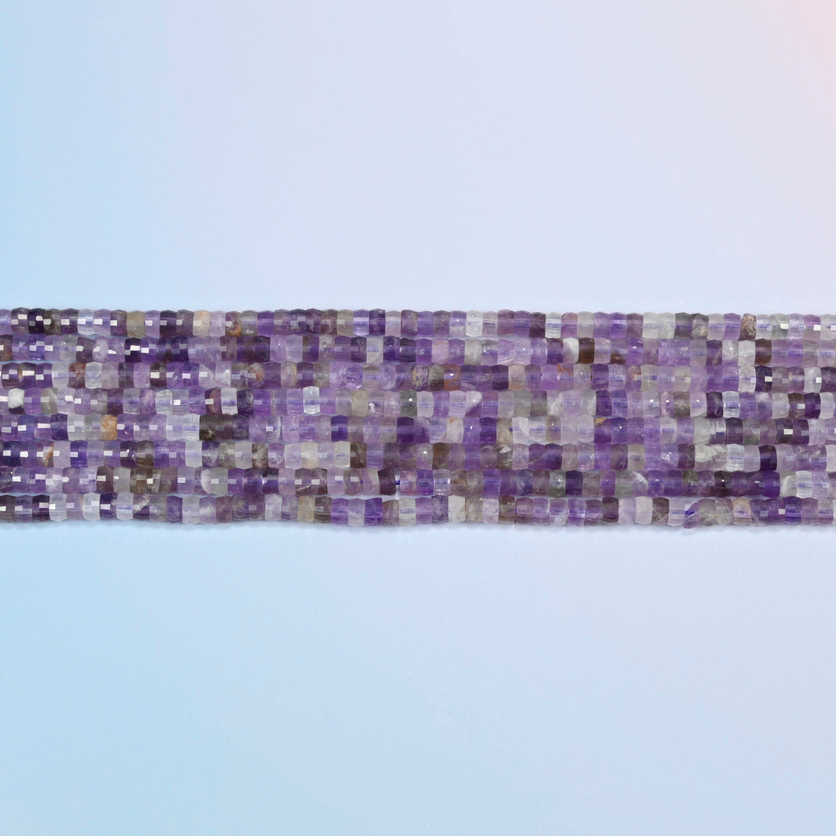 Several strands of amethyst faceted heishi disc beads laid in straight rows