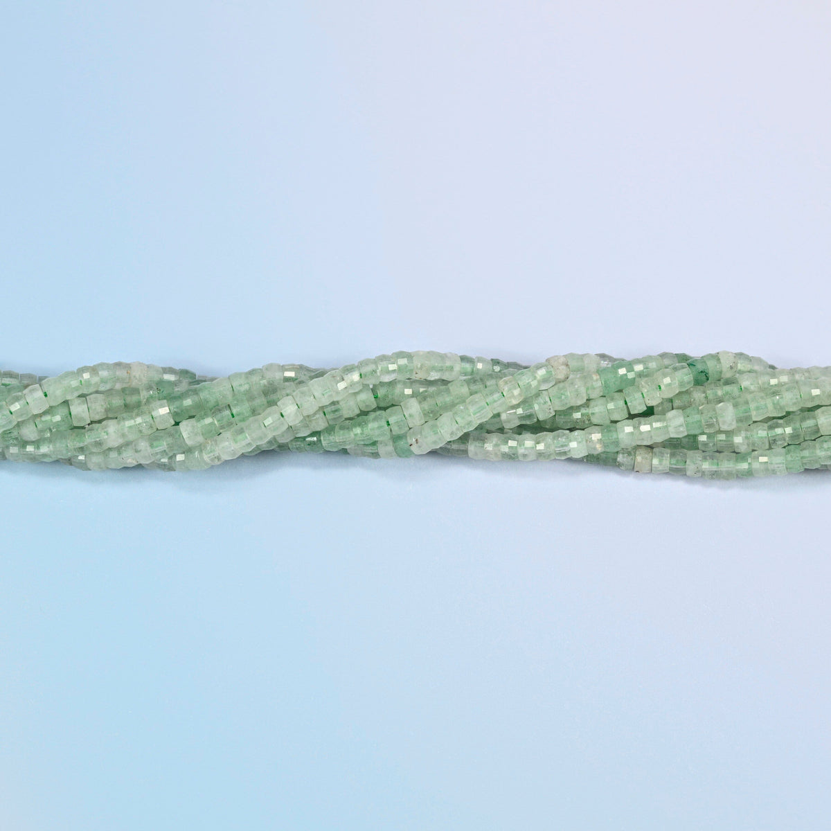 Strands of green strawberry quartz faceted heishi disc beads twisted together in a horizontal row