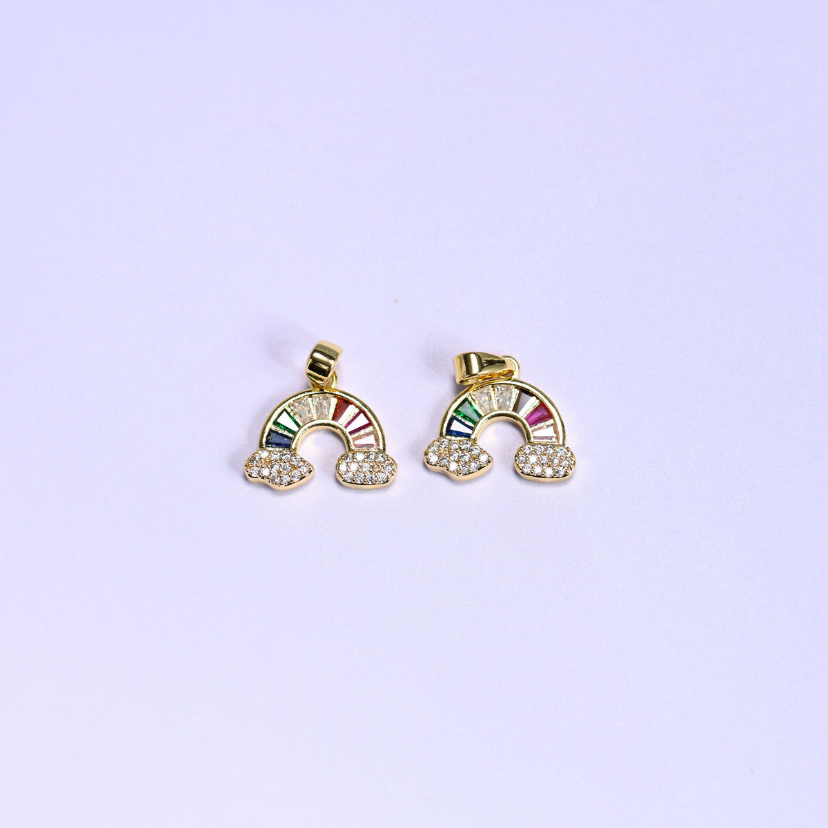 Two gold Rainbow Zirconia Charms side by side, 18K gold plated arcs of multicolor baguette zirconia resting on pave zirconia clouds.