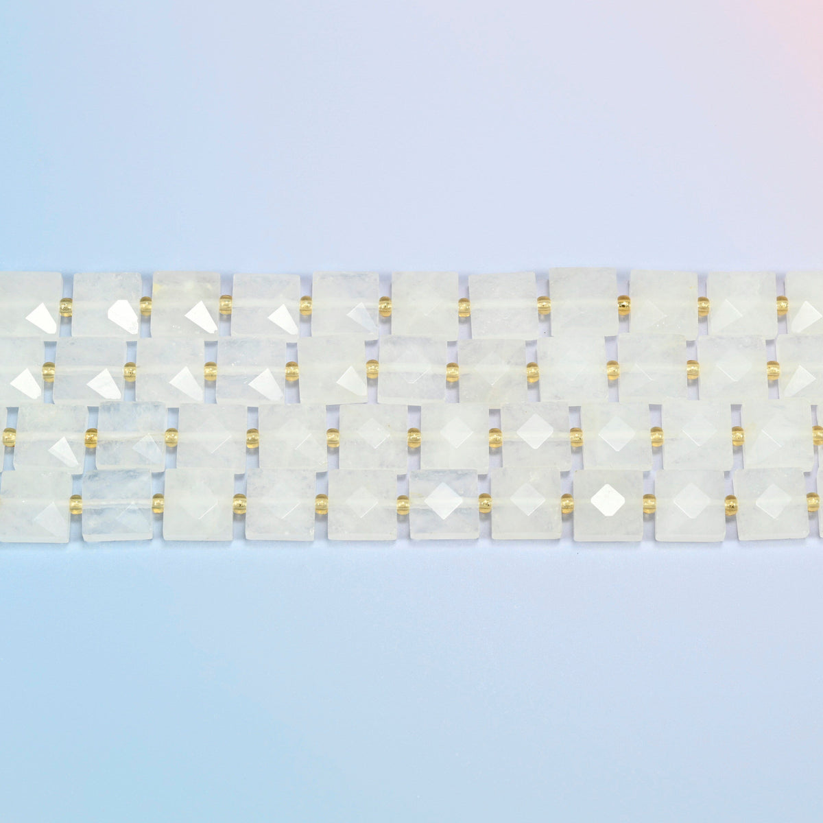 Several strands of clear quartz faceted flat square beads laid in straight rows