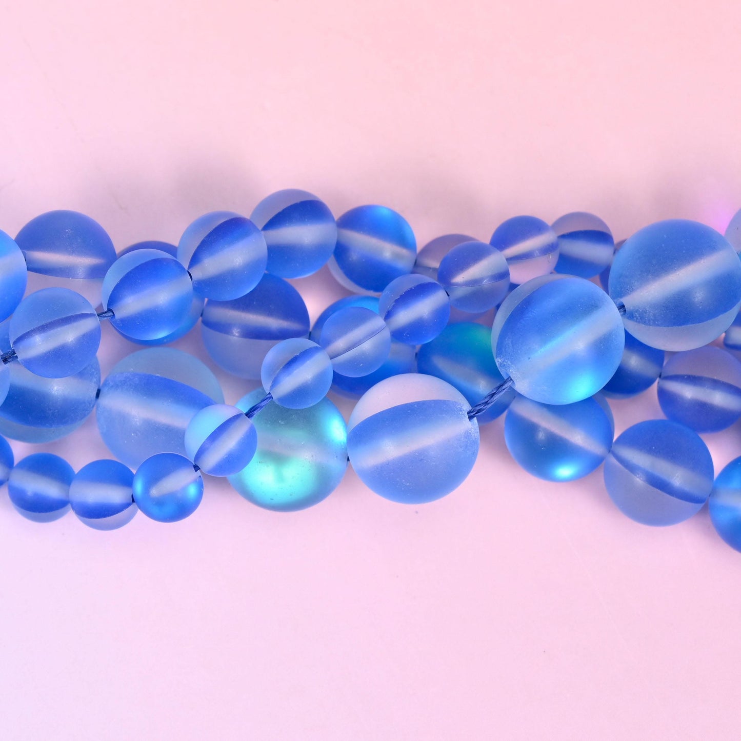 Cornflower blue glass rounds with a sanded frosted finish and an iridescent coating that reads as an inner light