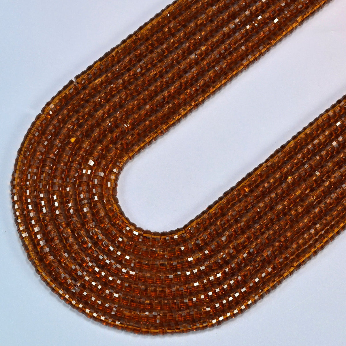 Brown glass faceted heishi disc beads in several strands curved into a wide U, transparent amber brown glass