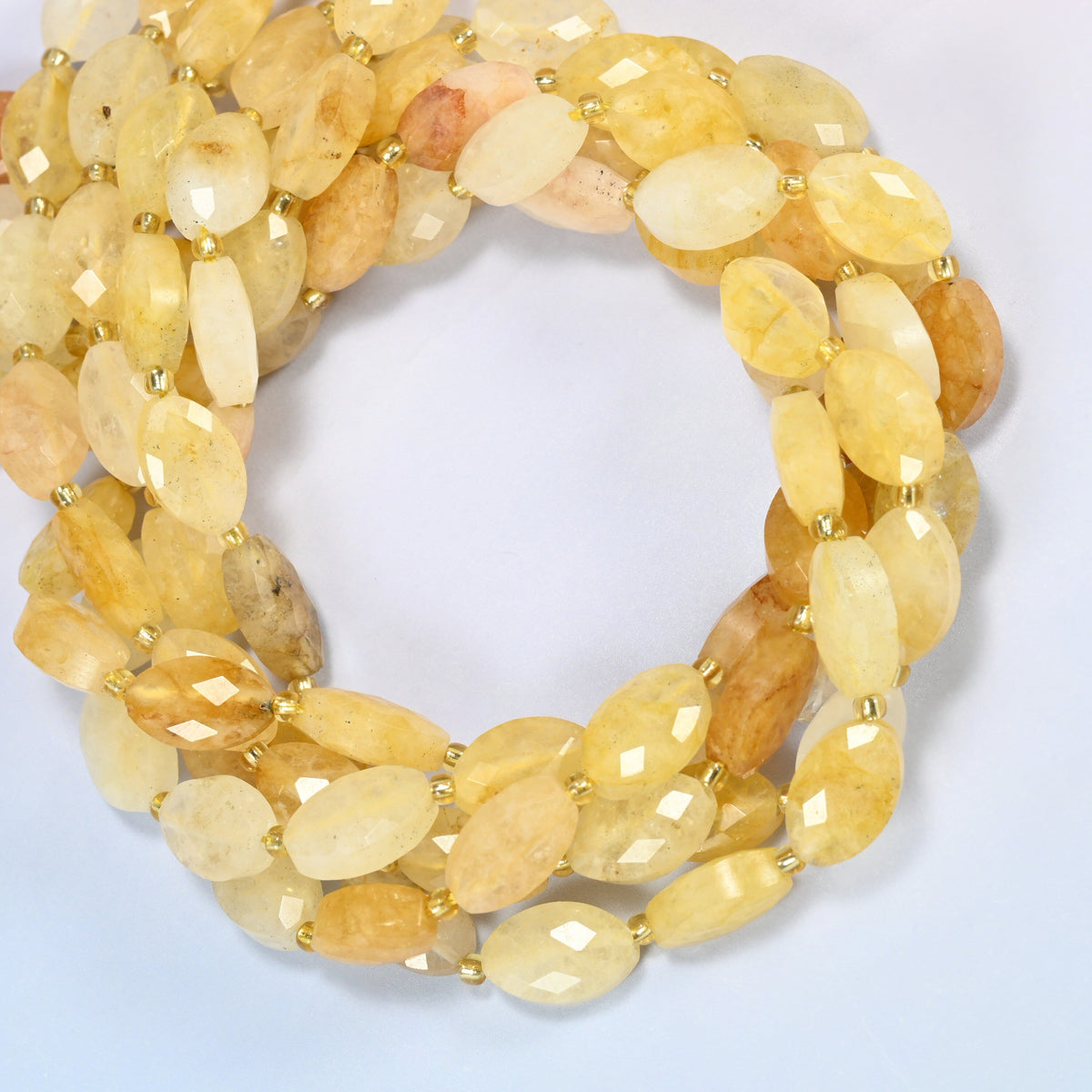 Golden healer quartz faceted flat oval beads coiled into overlapping loops, whole strands of warm golden stone