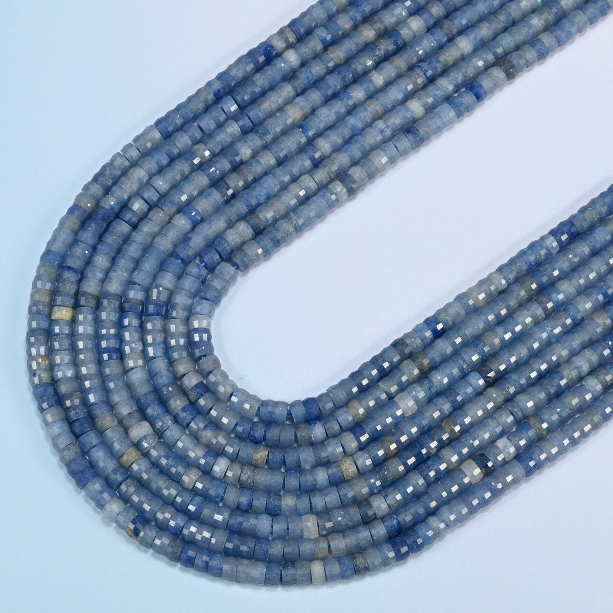 Blue aventurine faceted heishi disc beads in several strands curved into a wide U, light blue stone with a fine shimmer
