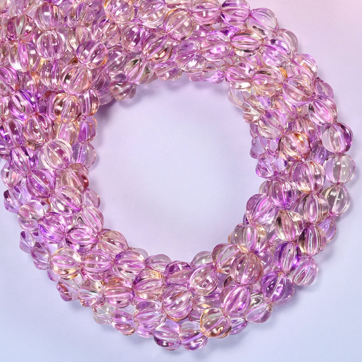 Clear purple gold pumpkin glass beads coiled into a densely packed ring with a small round opening.