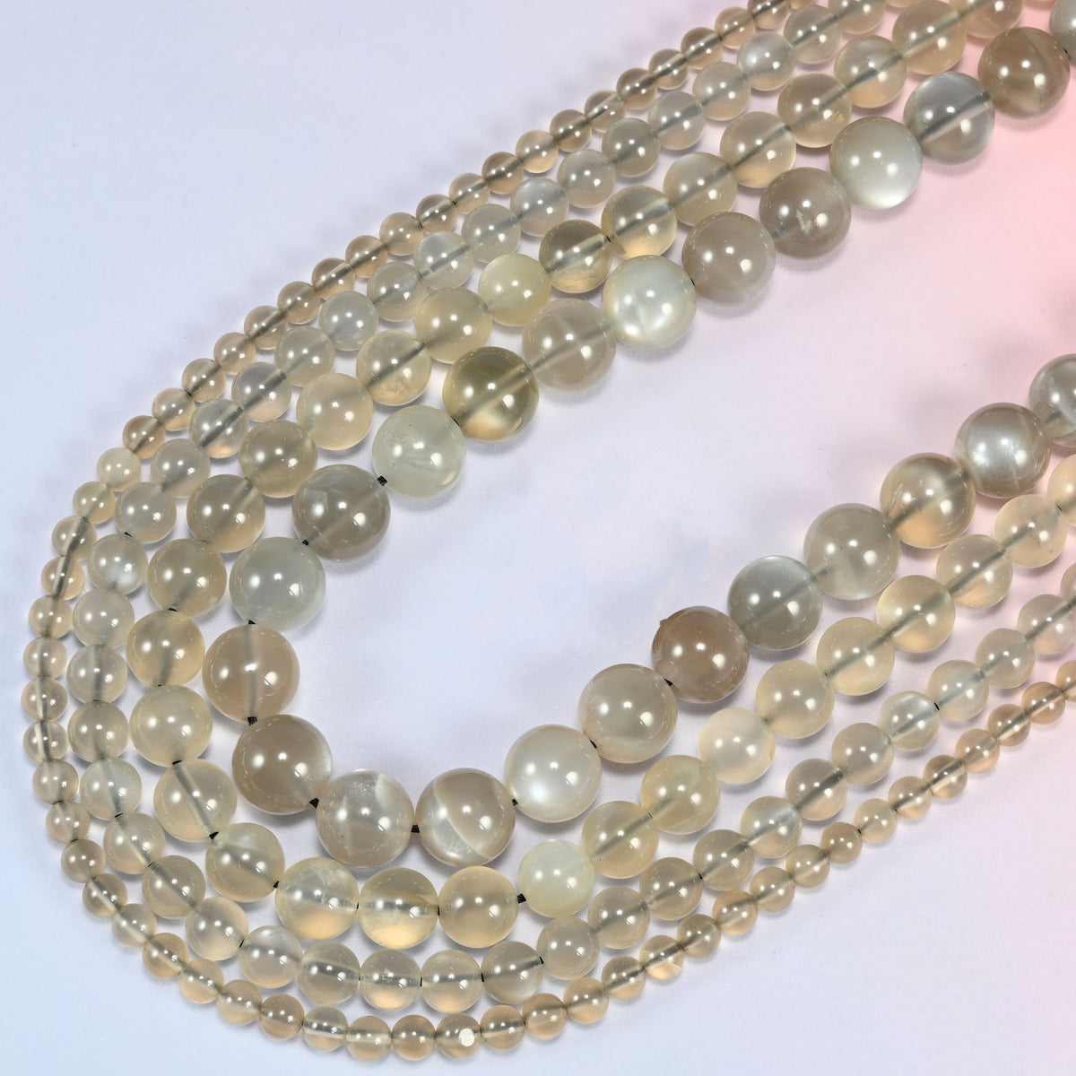 AAA Gray Labradorite smooth round beads curving in a long loop, light passing through the translucent stone