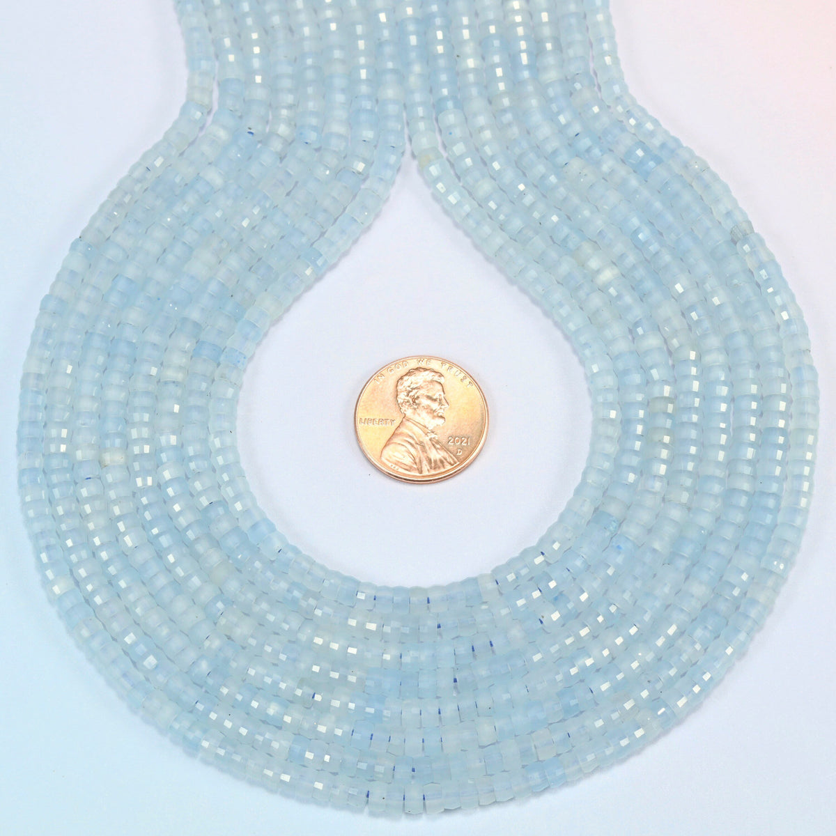 Aquamarine chalcedony faceted heishi disc strands formed into a teardrop loop around a US penny for scale
