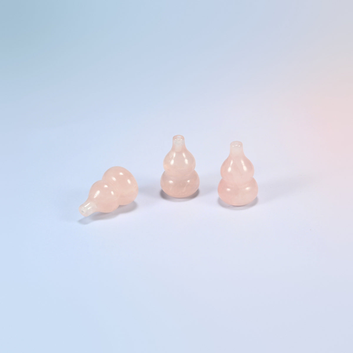 Natural rose quartz feng shui gourds, two standing and one lying down