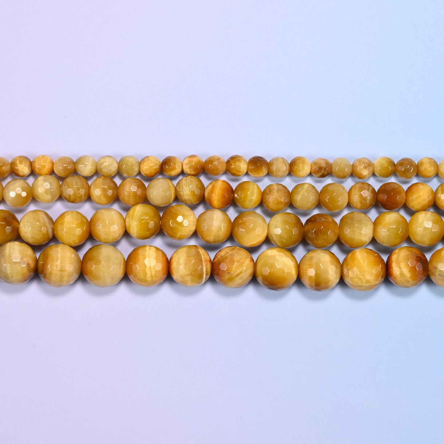Full 15-inch strand of golden brown gold tiger eye round beads laid out for jewelry making.