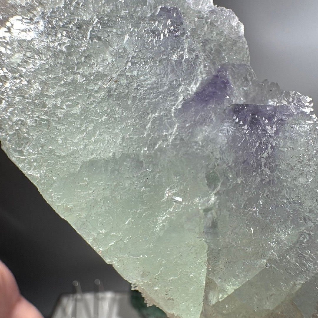 Side profile showing glassy cleavage planes and the broad flat base the specimen rests on