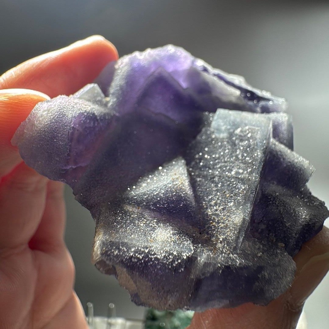 The 2.8 oz cluster held up close, quartz crystals sparkling across the purple cube faces