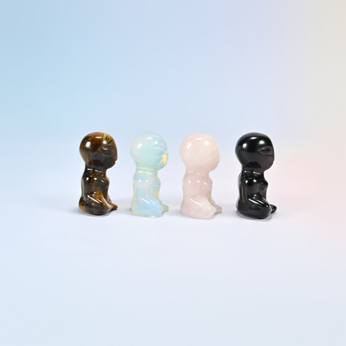Side view of four meditating alien gemstone figurines showing the big oval heads