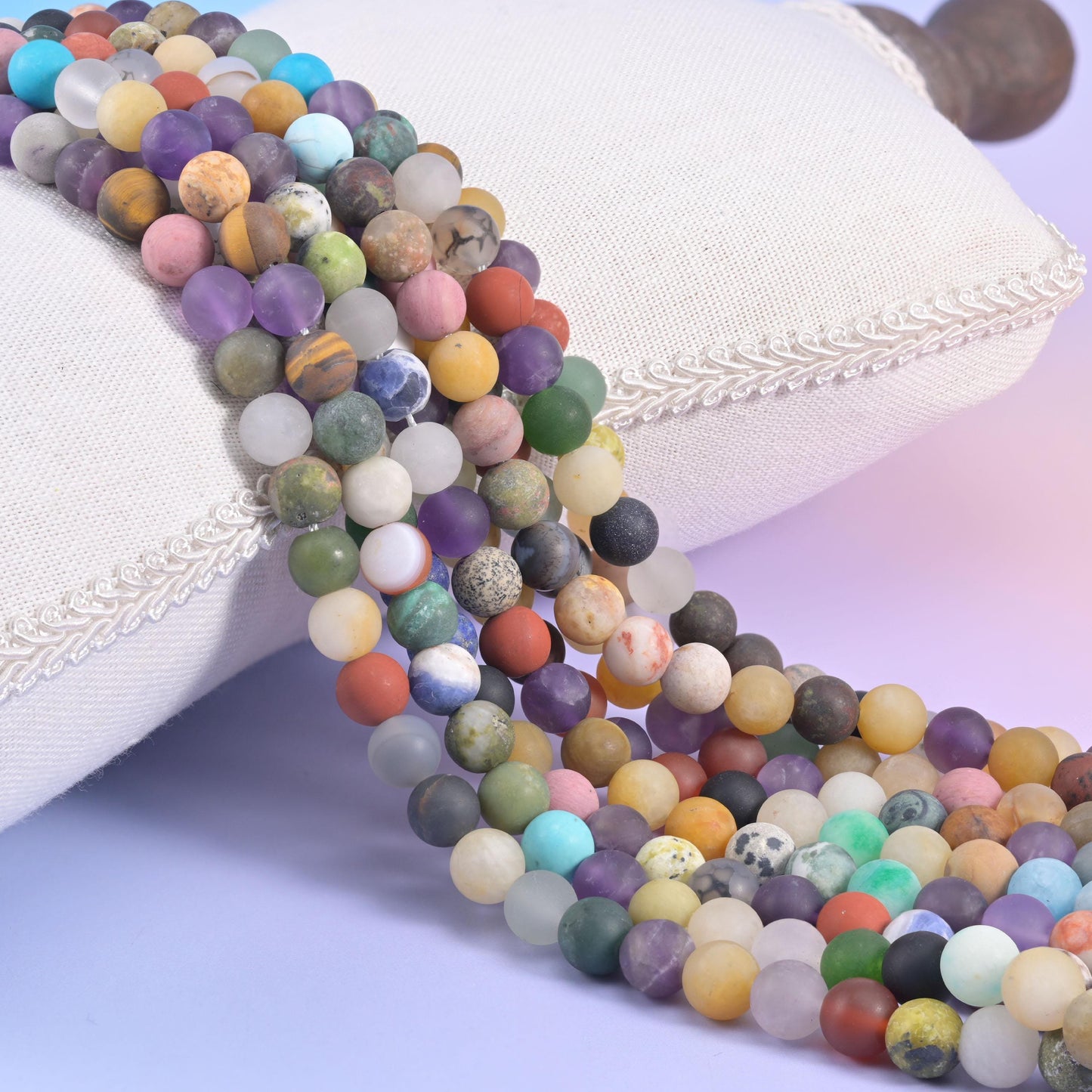 Multicoloured matte round bead strands spilling from a white cushion