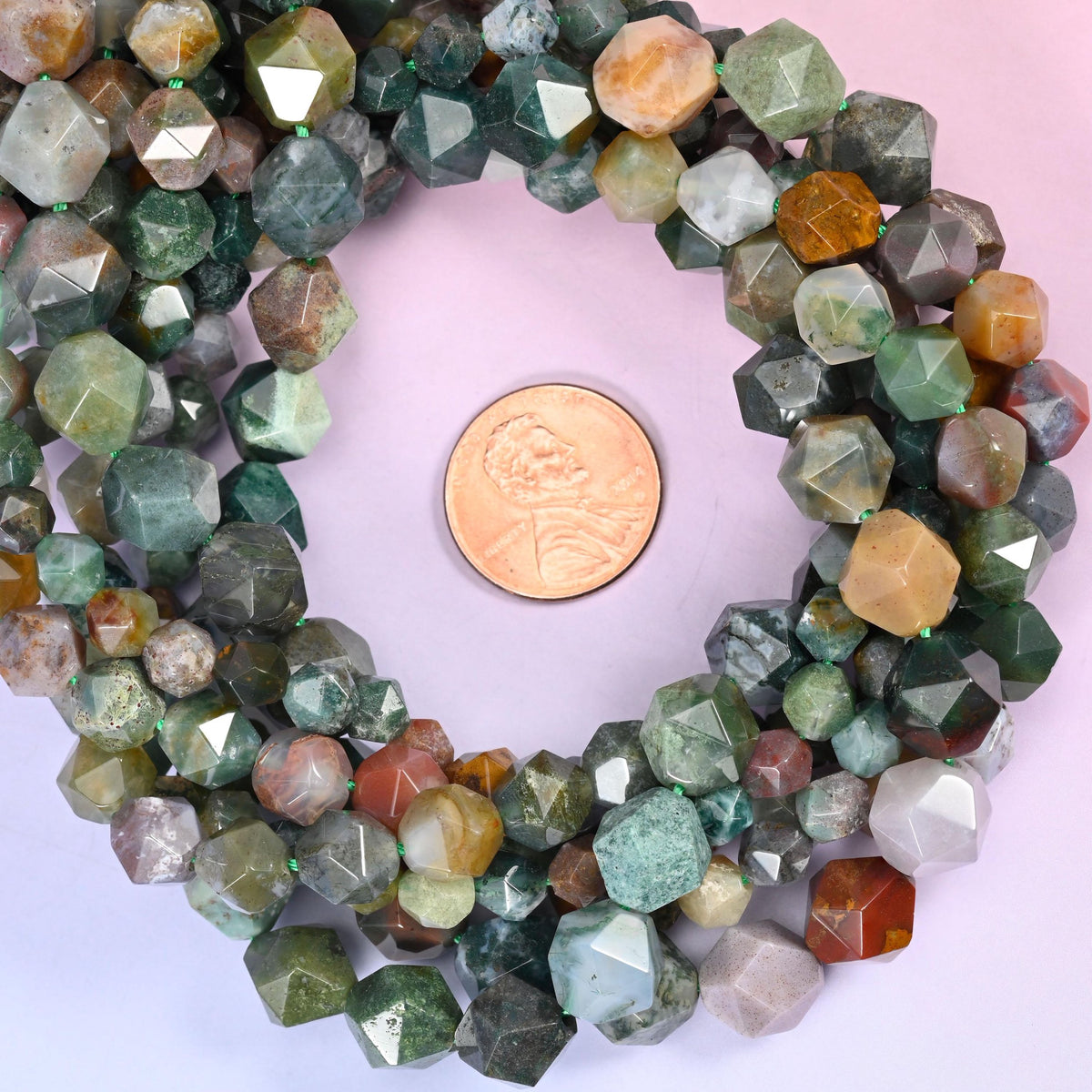 Indian Agate beads coiled around a US penny, drill hole approximately 1.0mm, mossy green with cream and rust banding