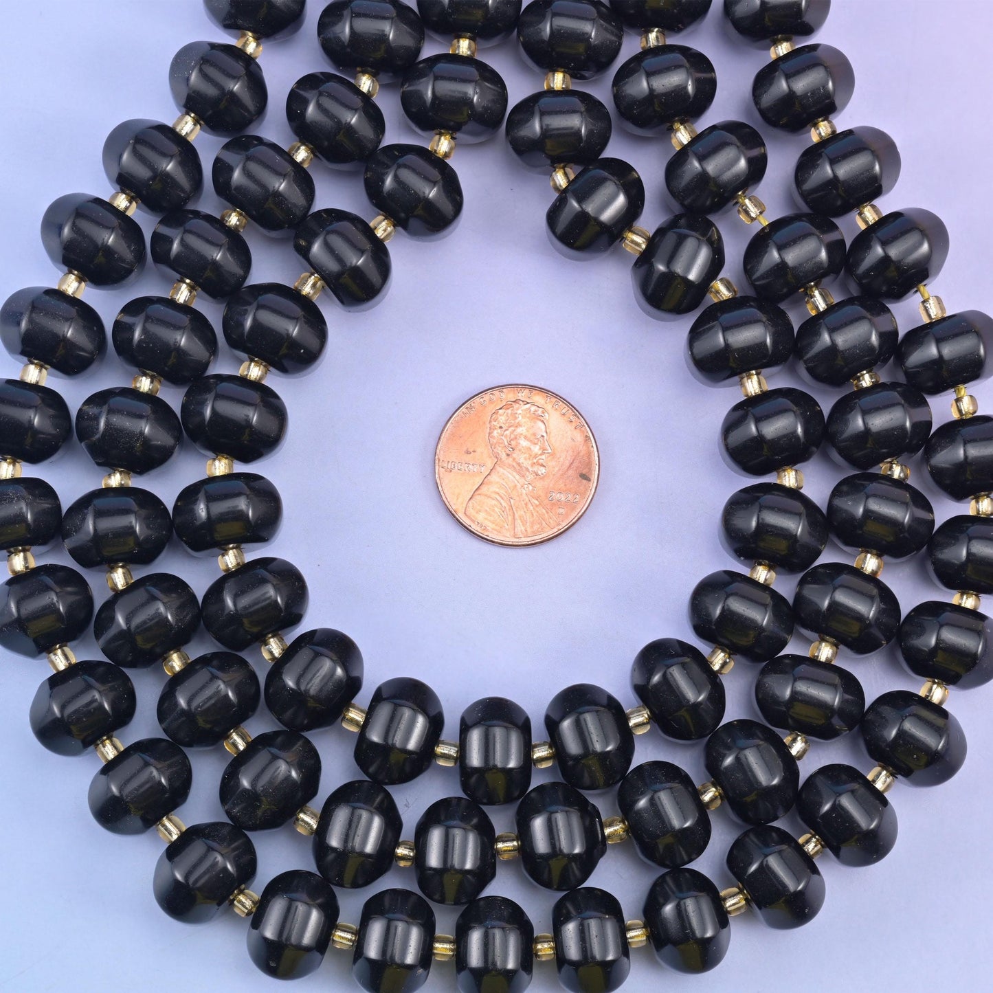 Pumpkin rondelles coiled around a penny, bead width clear against the flat coin