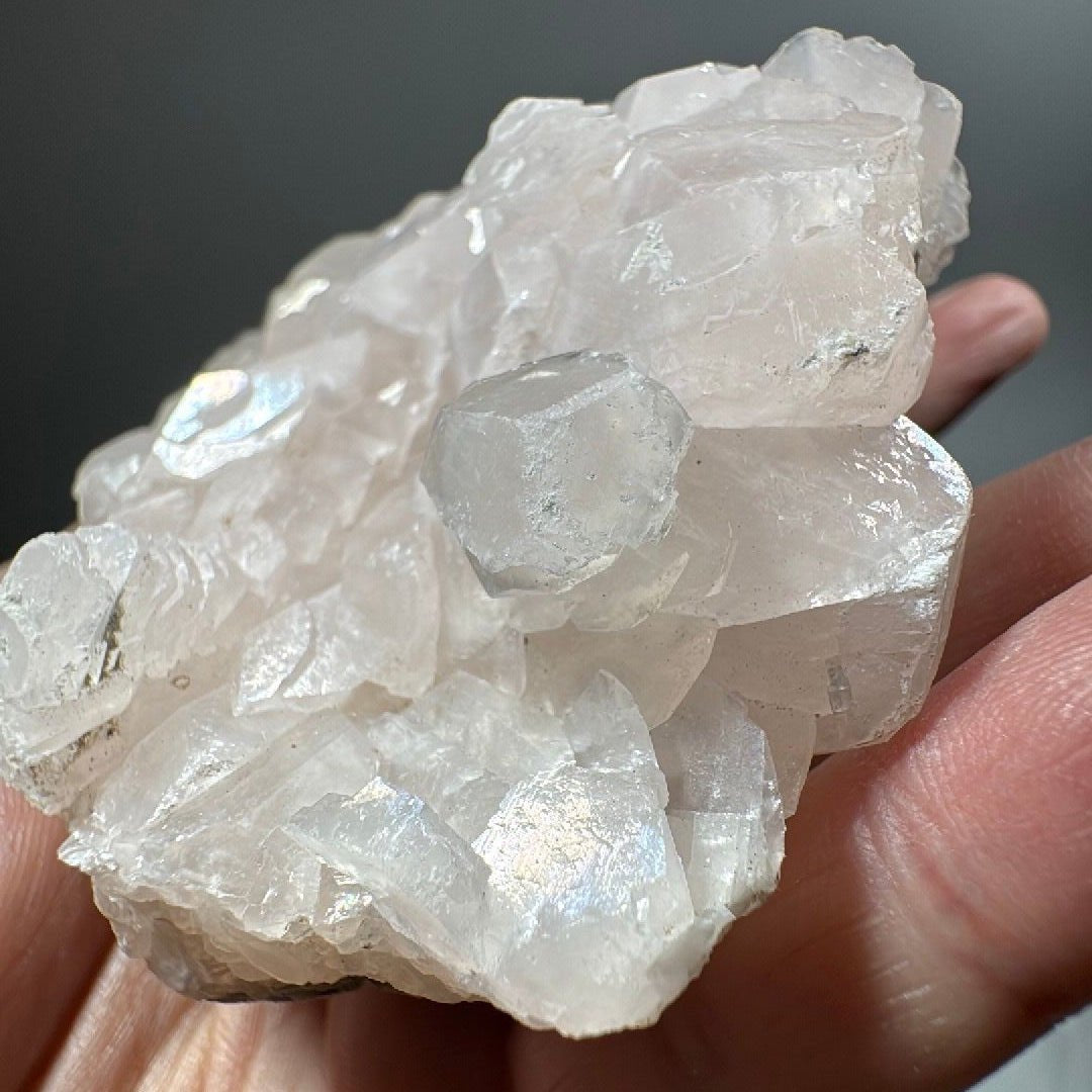 Hand-held view of the full calcite plate against a soft grey studio background