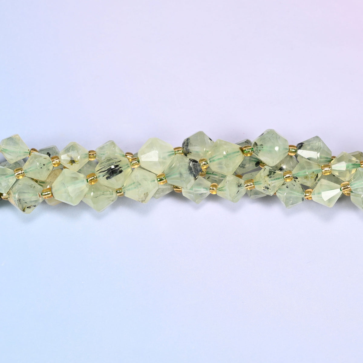 Macro close-up of Green Prehnite faceted bicone beads on a strand, showing the faceted cut and natural stone inclusions in detail.