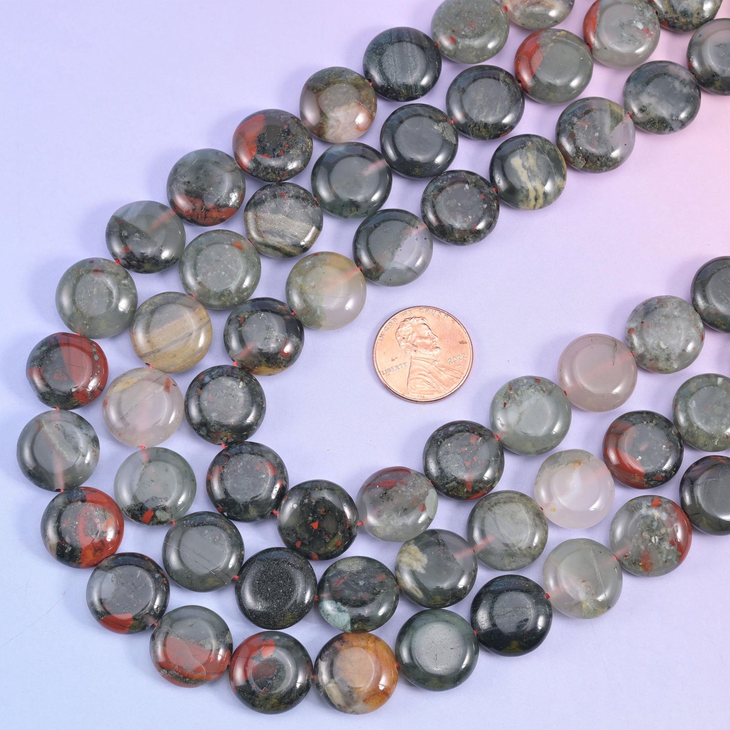 African Bloodstone coins arranged around a US penny for size comparison