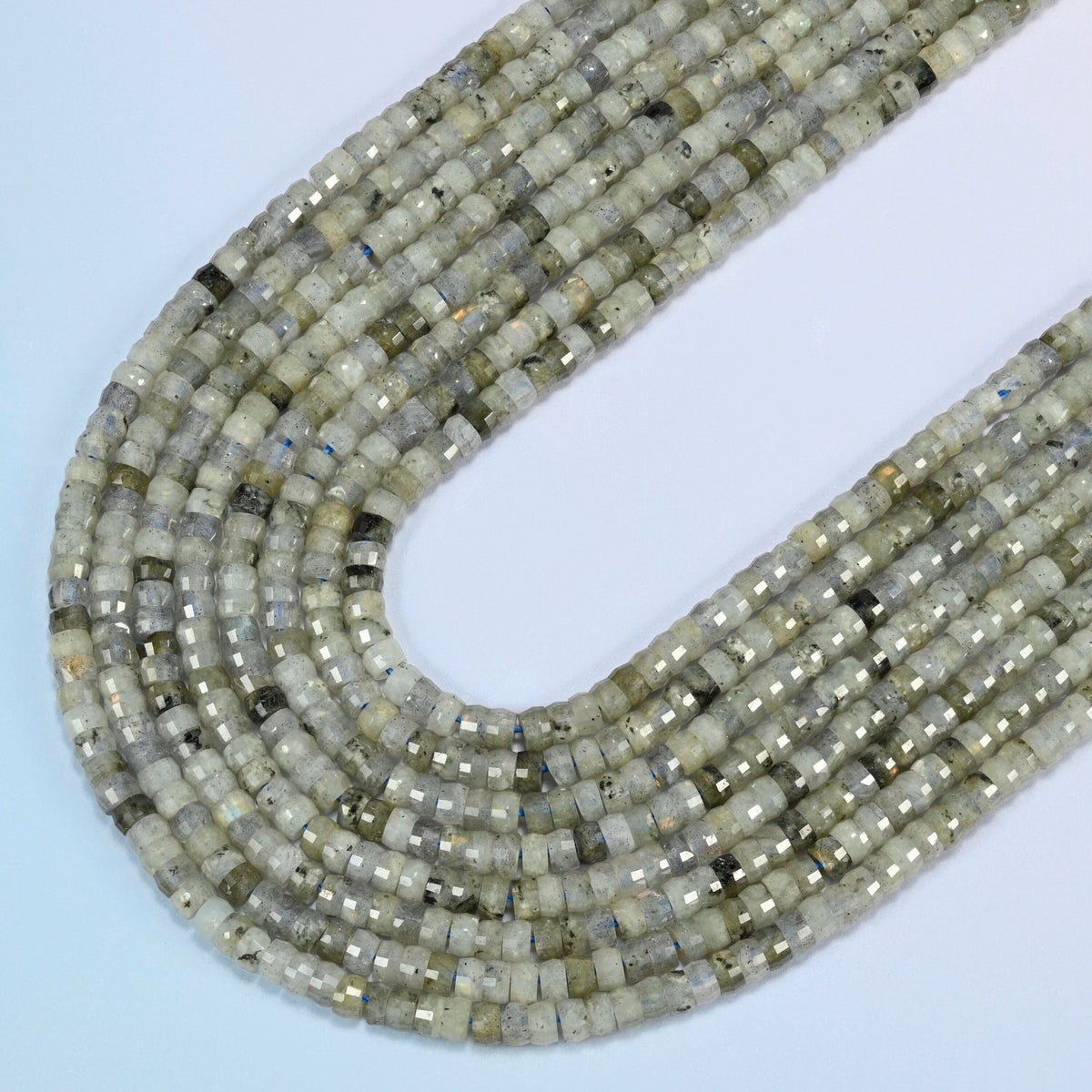 White labradorite faceted heishi disc beads in several strands curved into a wide U, light gray-green stone with dark specks