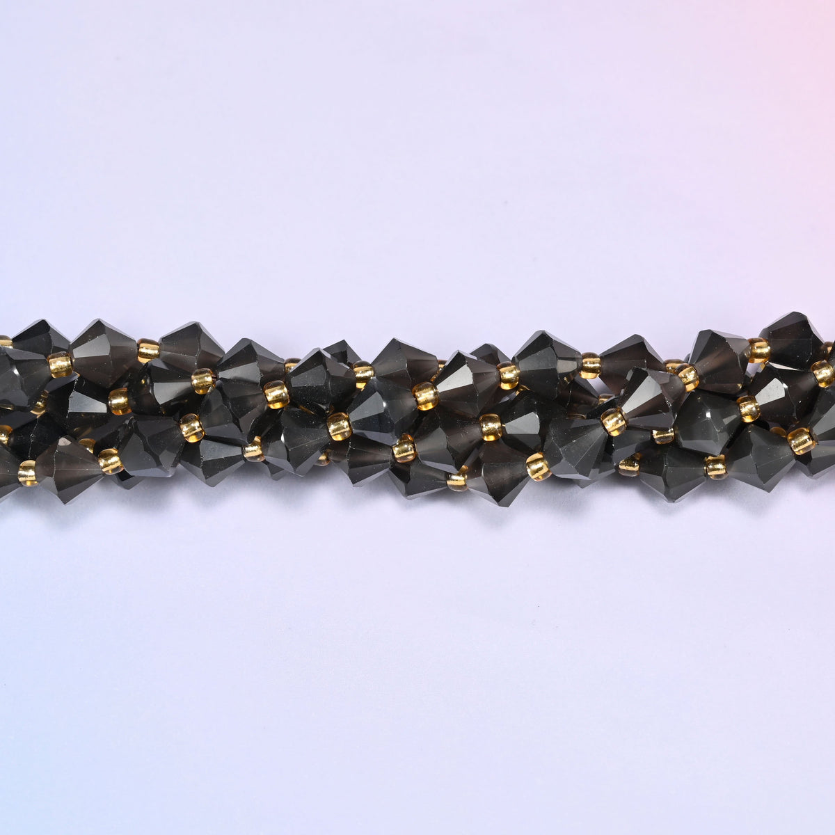 Ice Obsidian faceted bicone beads 8mm with gold-tone spacers, close-up of the strand laid straight