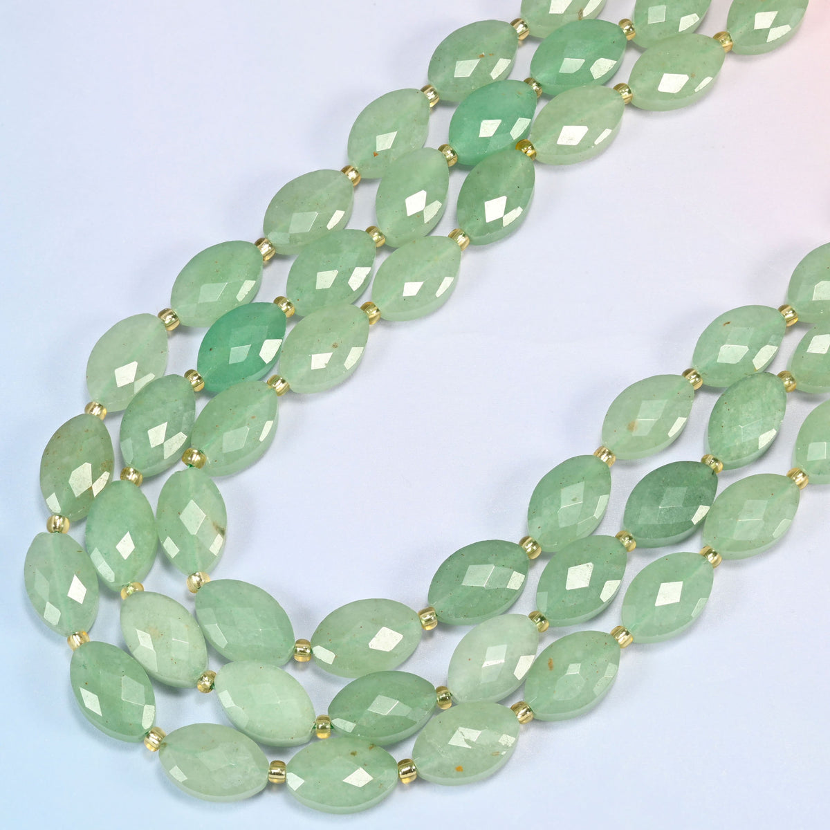 Green aventurine faceted flat oval beads in several strands curved into a wide U, soft mint and sage green stone