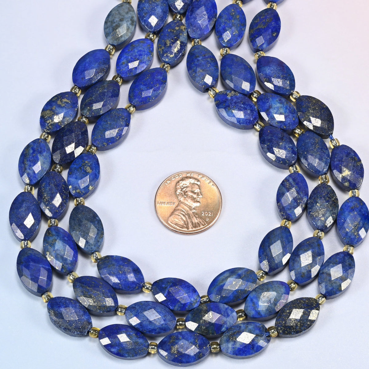Lapis lazuli faceted flat oval strands formed into a teardrop loop around a US penny for scale