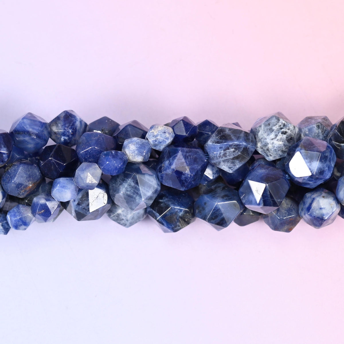 Deep royal blue marbled with chalky white and soft grey, cut into a geometric star pattern so each round is covered in broad flat panels that flash light as the strand turns. Three sizes to work with.
