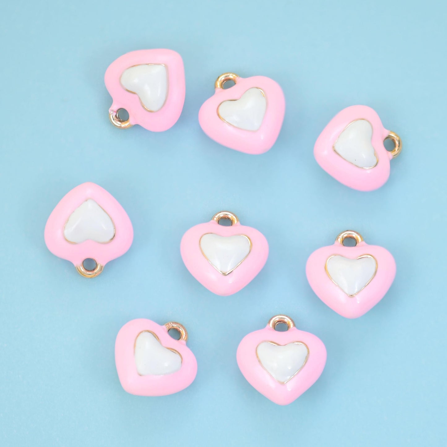 A small heart with a second heart nested inside it, both filled with enamel in contrasting tones and outlined in gold.…