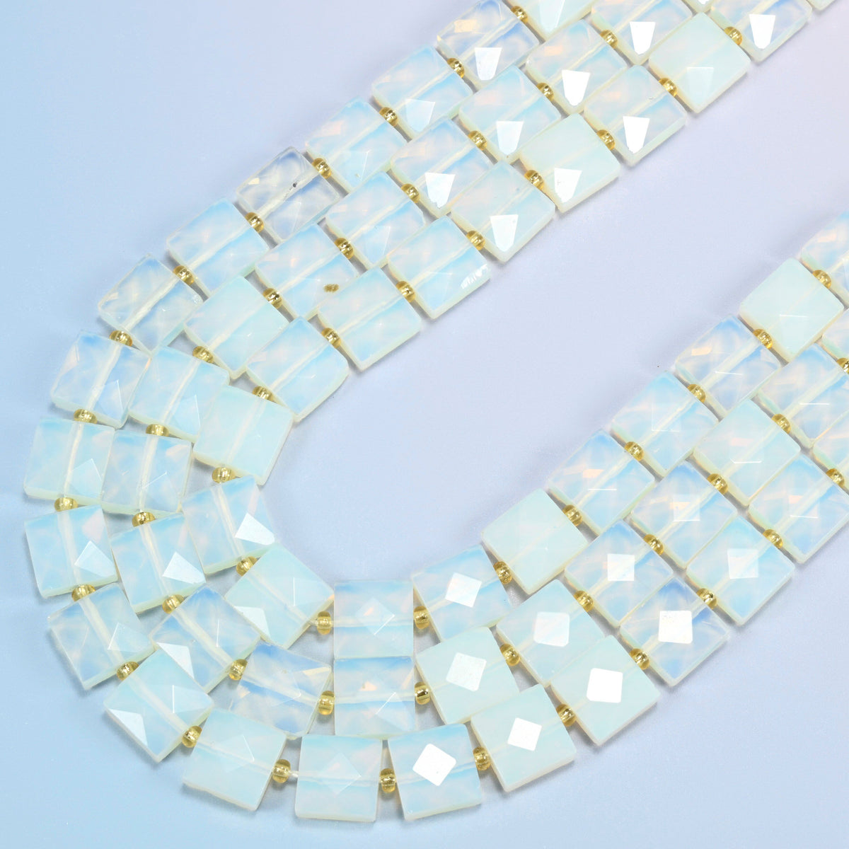 Opalite faceted flat square beads in several strands curved into a wide U, translucent milky white glass with a soft blue glow
