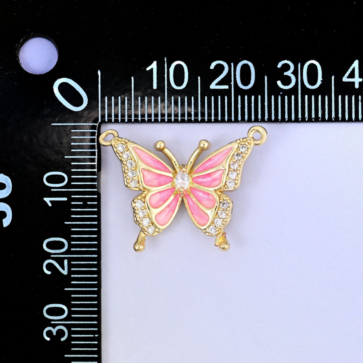Open gold wings filled with soft blush pink enamel and outlined in clear zircon