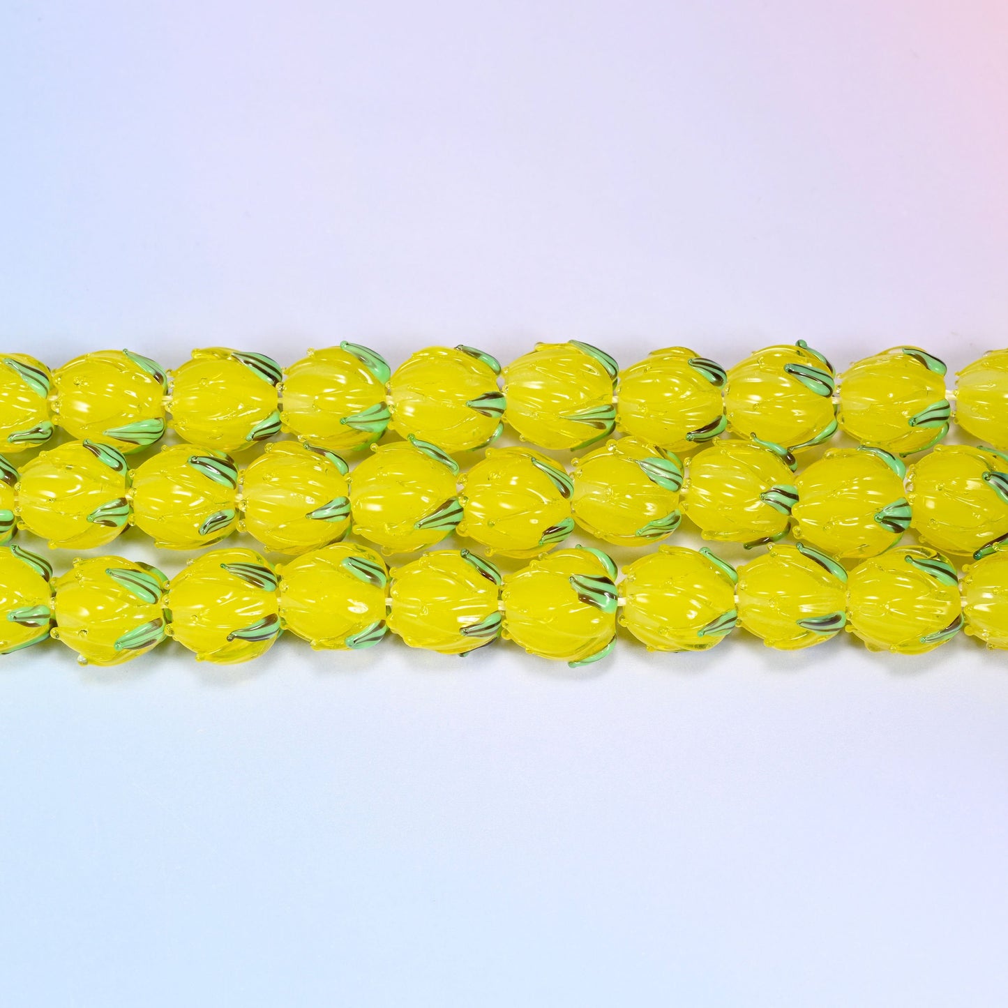 Yellow tulip bud glass beads in translucent yellow with a green leaf detail at the base